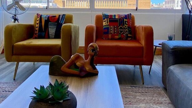 Un salon moderne avec deux canapés, une table basse et une grande fenêtre offrant une vue sur une montagne et le paysage urbain.