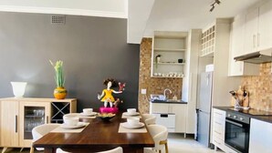 Une cuisine moderne avec des meubles blancs, une table à manger en bois et une figurine décorative.