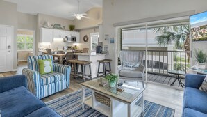 Een ruime woonkamer met een groot raam, een balkon en een keukenhoek.