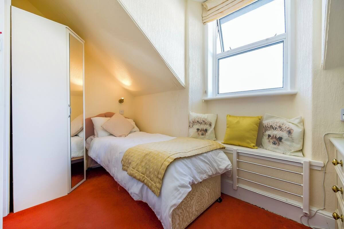 A bedroom with a bed, a window, a radiator, and a wardrobe.