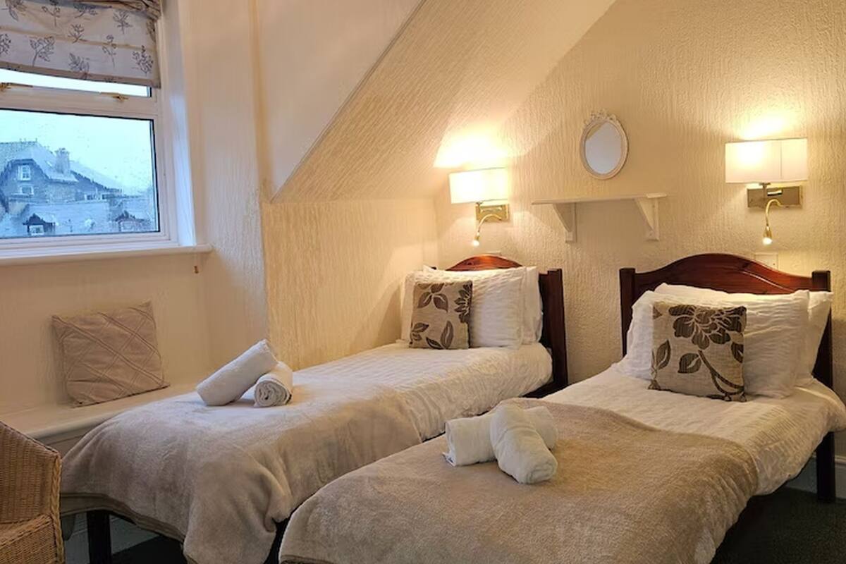 A room with two beds, a window with a view, and a chair.