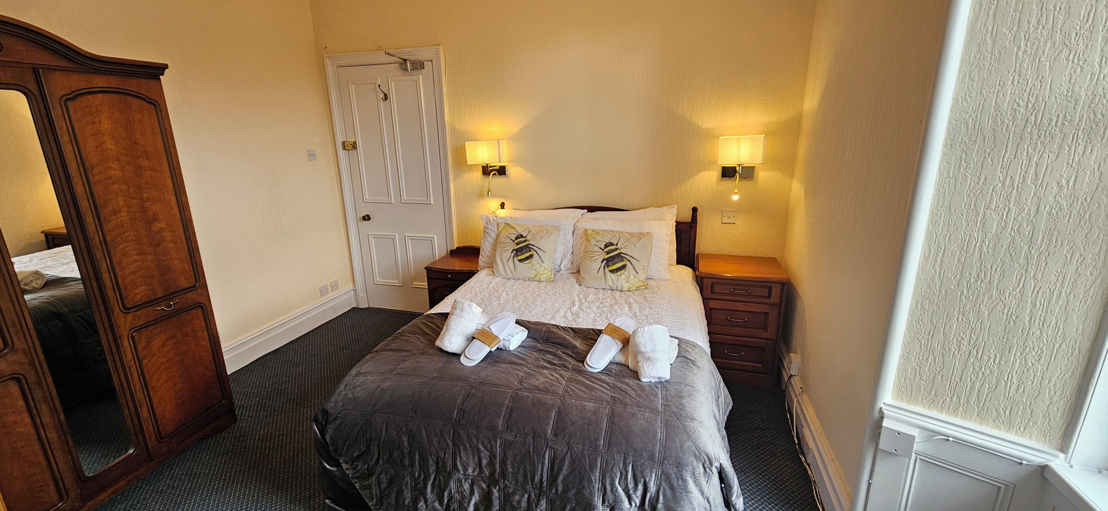 Habitación de hotel con cama, dos mesitas de noche, un armario y una puerta.