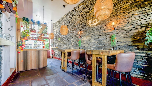 A restaurant interior with stone walls, hanging wicker lamps, and bar stools. - Ambleside Guest House (Ambleside)