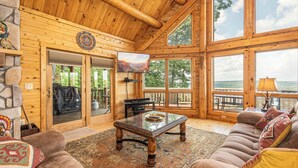 Una cabaña de madera espaciosa con una amplia sala de estar, chimenea y vistas al exterior.