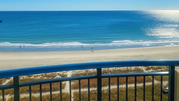 Vista a la playa desde un balcón con barandilla.