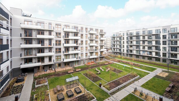 A modern apartment complex with multiple balconies, a central courtyard with seating and greenery, and a pedestrian pathway. - Praga Południe Homely Apartment (Warszawa)