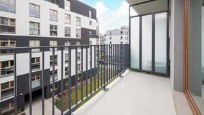 A balcony with a view of adjacent buildings, a glass door, and a metal railing. - Praga Południe Homely Apartment (Warszawa)