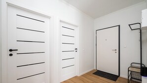 A hallway with two white doors, one with horizontal handles and the other with vertical handles. - Praga Południe Homely Apartment (Warszawa)