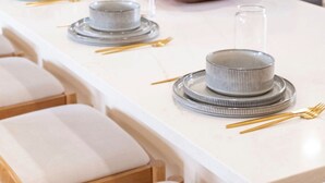 Une cuisine moderne avec un plan de travail blanc, des appareils en acier inoxydable et un saladier en bois comme élément décoratif central.