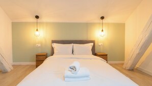A neatly made bed with a folded towel, two bedside tables, and wall-mounted lamps. - Fabryczna City Apartment (Katowice)