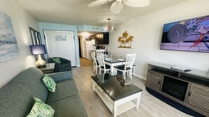 A living room with a sofa, coffee table, TV, and a dining area with chairs and a table. - PALM TREE PARADISE/PRIME LOCATION (Myrtle Beach)