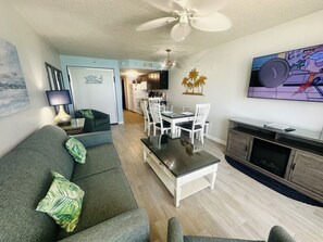 A living room with a sofa, coffee table, TV, and a dining area with chairs and a table. - PALM TREE PARADISE/PRIME LOCATION (Myrtle Beach)