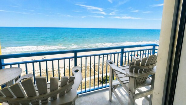 A balcony with a view of the ocean, a table, and chairs. - PALM TREE PARADISE/PRIME LOCATION (Myrtle Beach)