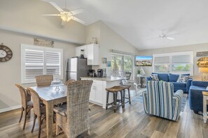 A spacious living area with a dining table, wicker chairs, a blue sofa, and a striped armchair. - Perfect for large groups, Steps to the Beach. Private Pool & Putting Green. (Siesta Key)