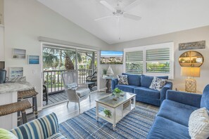 Uma sala de estar ampla com um sofá azul, uma mesa de centro e vista para o exterior.