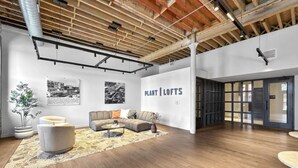 A spacious office with a high ceiling, exposed beams, a large sofa, and a sign reading 'PLANT | LOFTS'. - Sleepover | Stylish 1BD/1BA Loft - Newton (Newton)