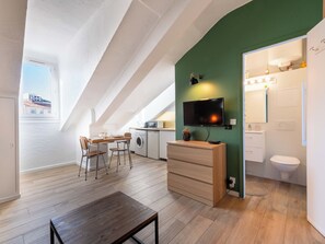 Eine moderne Wohnung mit Essbereich, Küchenzeile und Bad.