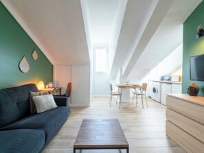 Eine moderne Wohnung mit Essbereich, einer Küchenzeile und einem Wohnraum mit Sofa und Couchtisch.
