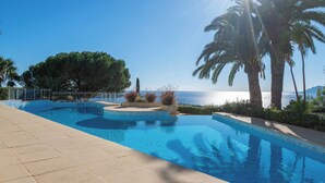 A swimming pool with a clear view of the sea, surrounded by palm trees and a tiled deck. - 2-Br Panoramic Views – Top Floor, Cannes (Cannes)