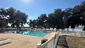 A swimming pool with a white fence, lounge chairs, and a view of a lake. - #8 2-bedroom cottage in Salt Springs Under New Management, ice machine on site. (Salt Springs)