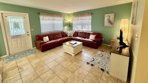 A living room with a brown leather sofa, a white coffee table, and a patterned rug. - #8 2-bedroom cottage in Salt Springs Under New Management, ice machine on site. (Salt Springs)