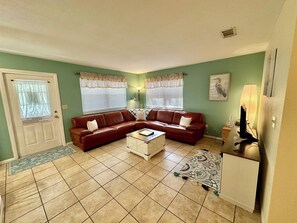 A living room with a brown leather sofa, a white coffee table, and a patterned rug.