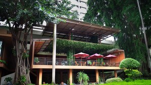 A two-story building with a covered outdoor seating area, surrounded by lush greenery and trees. - Hotel Borobudur Jakarta (Jakarta)