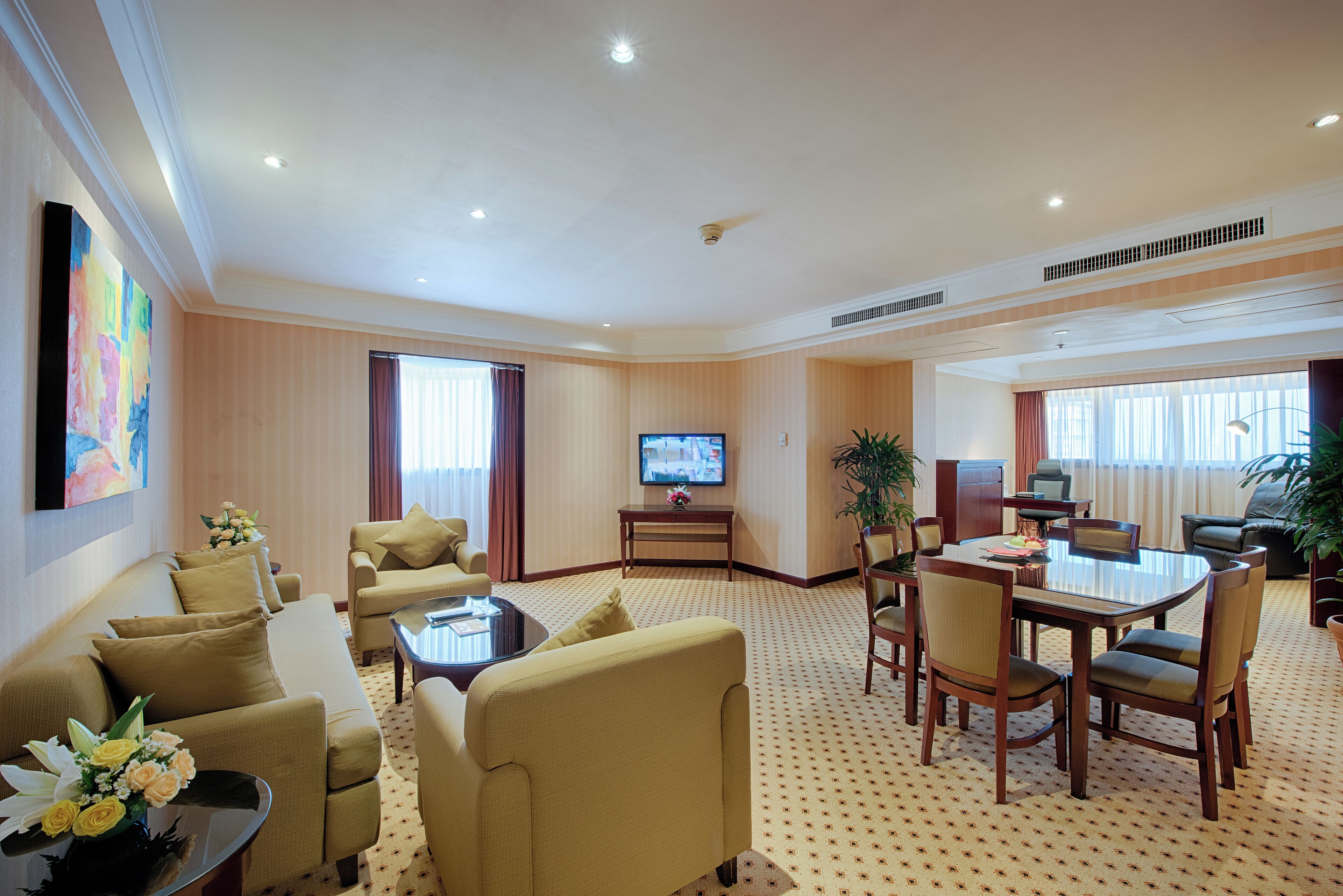 Habitación de hotel con zona de estar, mesa de comedor y televisor.