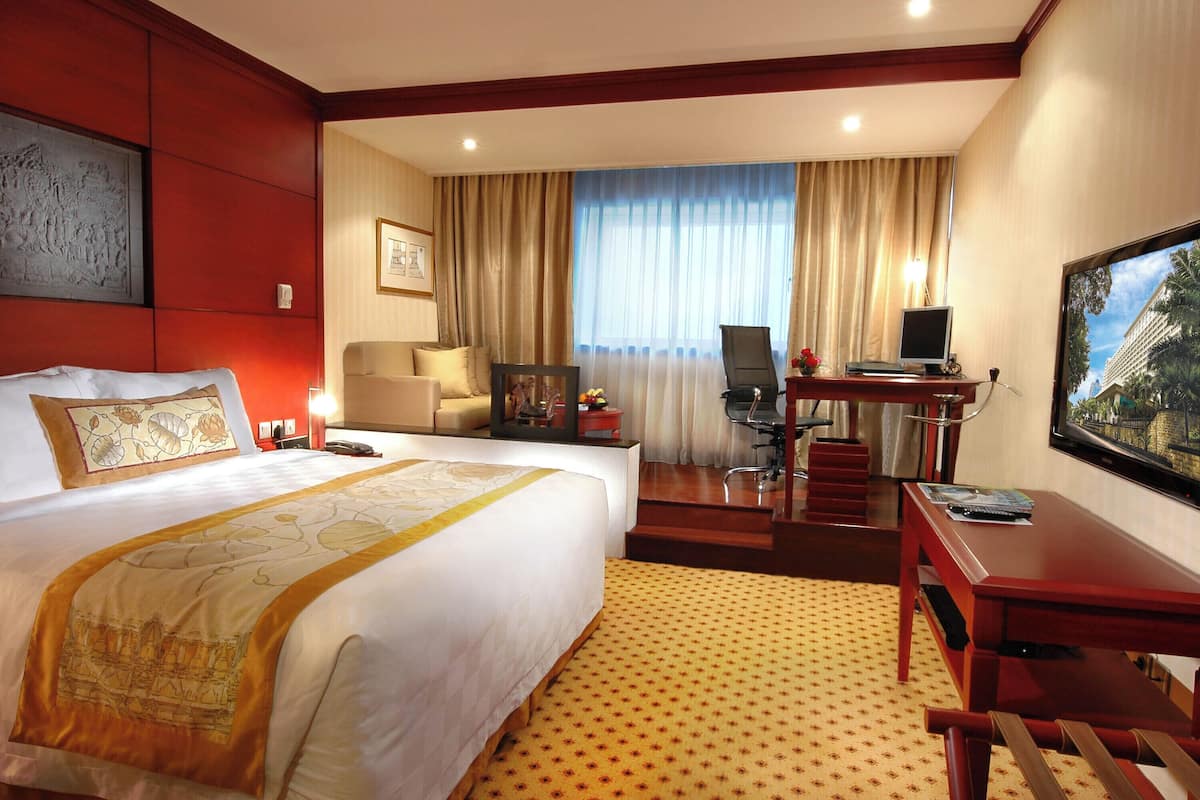Una habitación de hotel con una cama grande, un escritorio con computadora, una silla y un televisor.