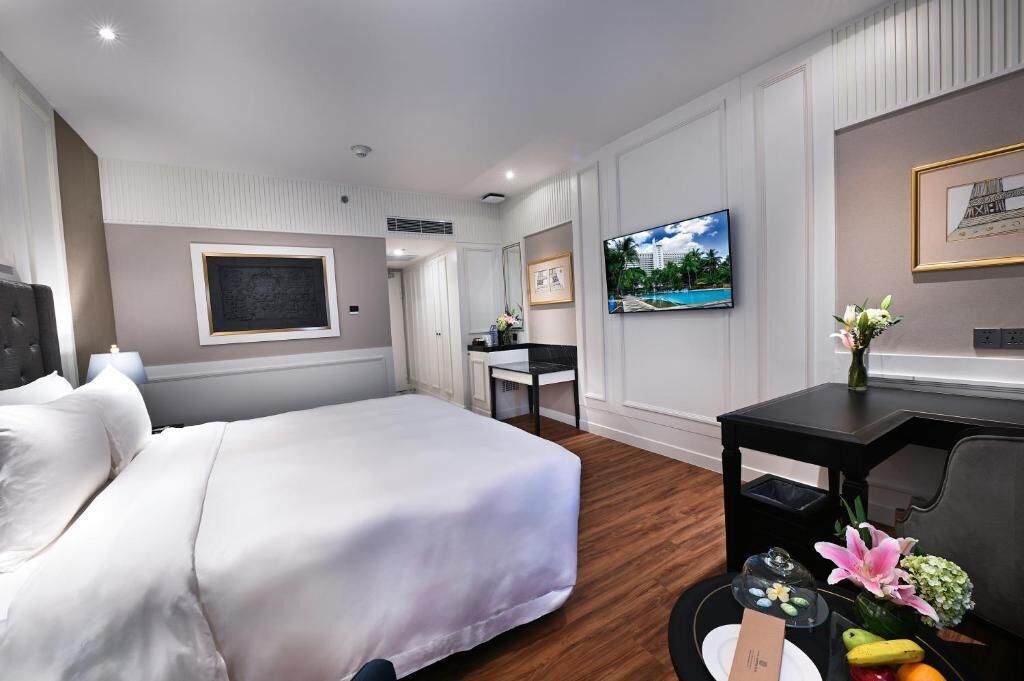 Habitación de hotel con cama, escritorio, televisión y un cuadro en la pared.