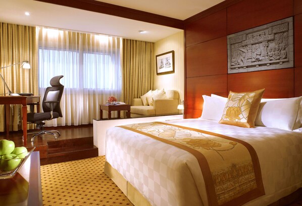 Una habitación de hotel con una cama grande, un escritorio con silla, un sofá y una mesa de comedor.