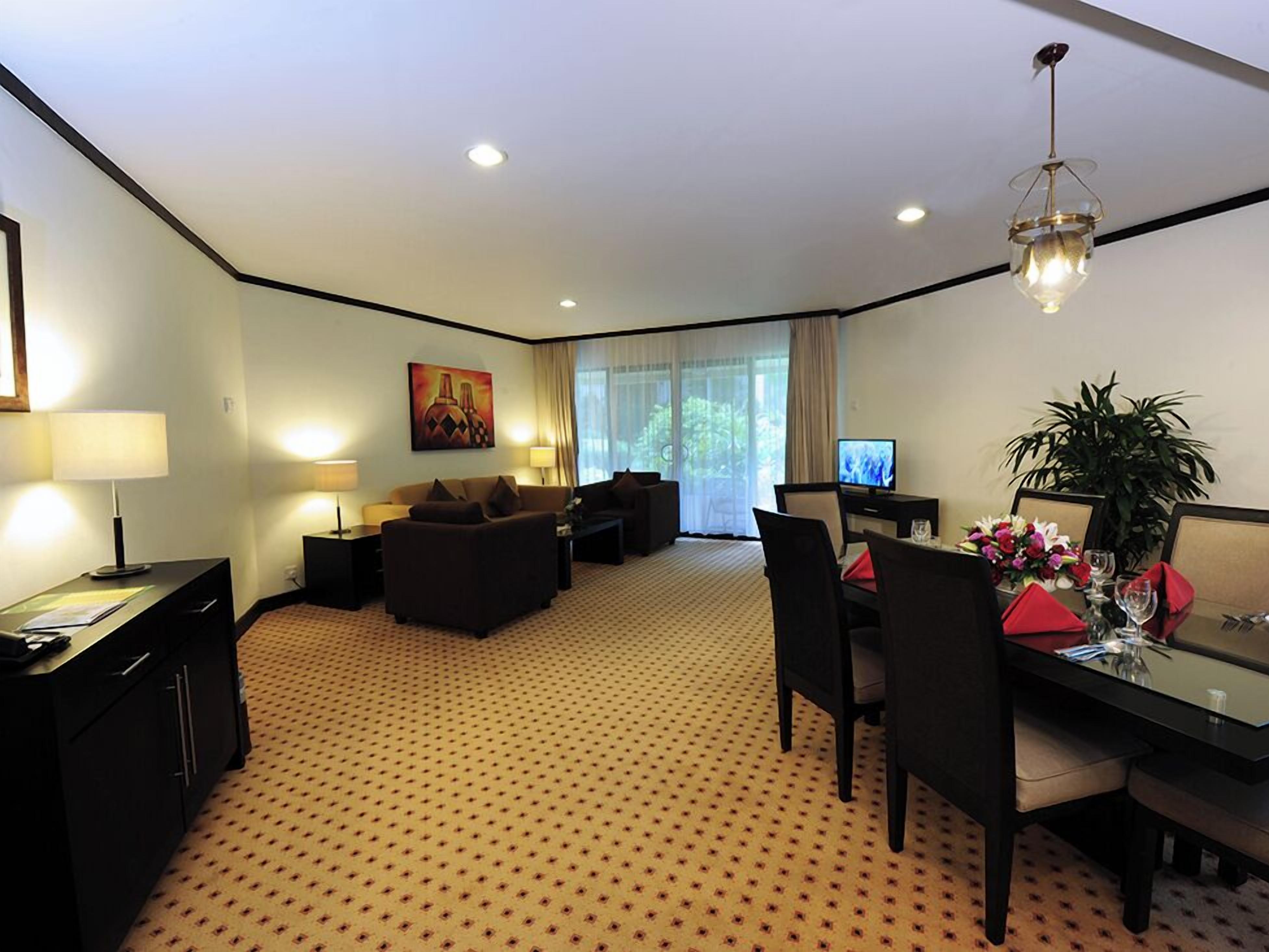 A hotel room with a living area, dining table, and a TV.