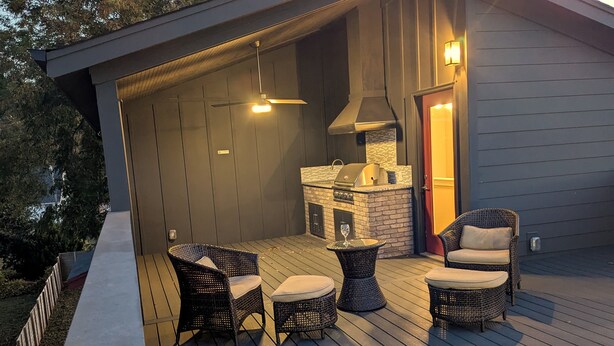 An outdoor deck with wicker furniture, a grill, and a glass table. - Modern Raleigh Downtown Rooftop Skyline View SFH-R (Raleigh)