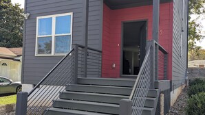 A two-story building with a red door and a staircase leading to the entrance. - Modern Raleigh Downtown Rooftop Skyline View SFH-R (Raleigh)