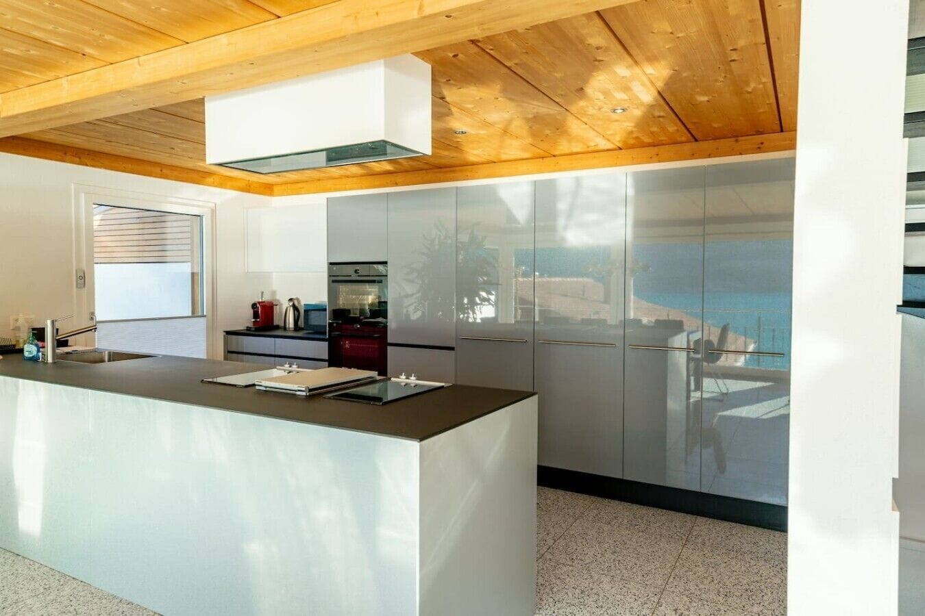 Una cocina moderna con una isla central, electrodomésticos de acero inoxidable y techo de madera.
