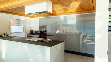 Una cocina moderna con una isla central, electrodomésticos de acero inoxidable y techo de madera.