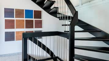 Una escalera moderna con barandas negras y una serie de baldosas cuadradas en la pared.