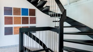 A modern staircase with black railings and a series of square tiles on the wall.