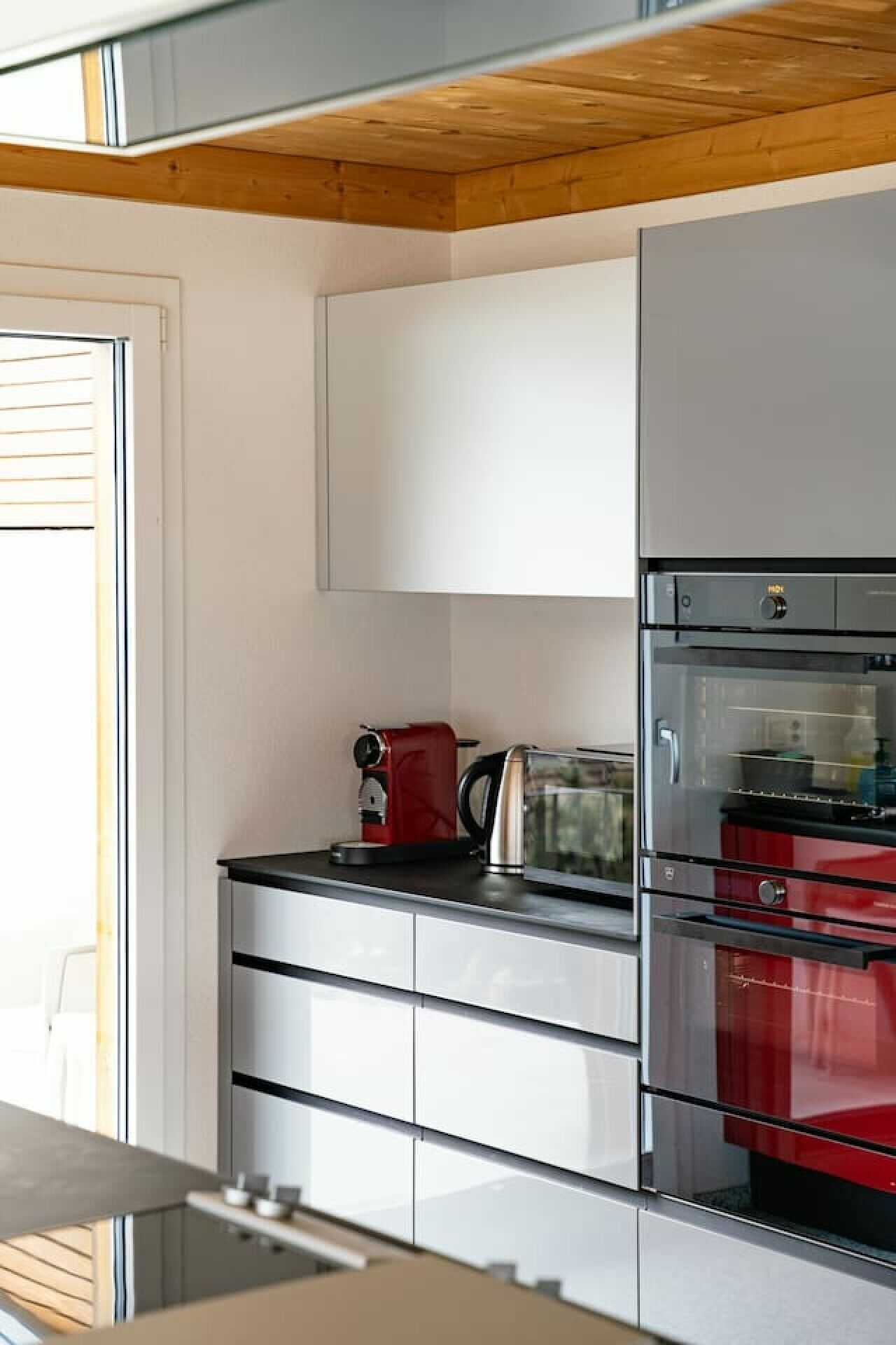 Una cocina moderna con horno empotrado, cafetera y tostadora.
