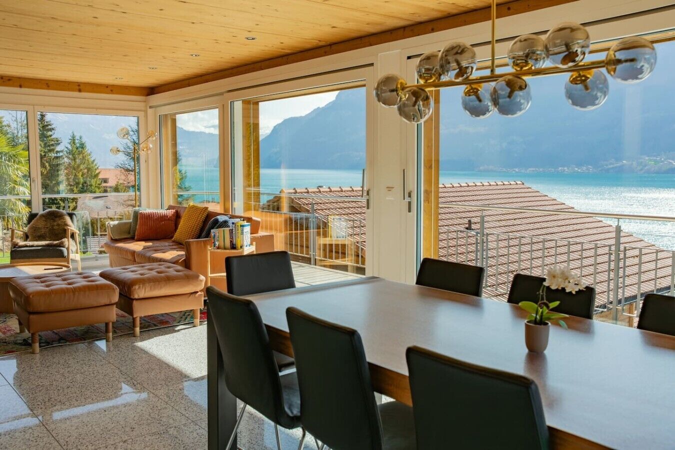 Un intérieur moderne comprenant un coin repas, des canapés et une vue sur la mer.