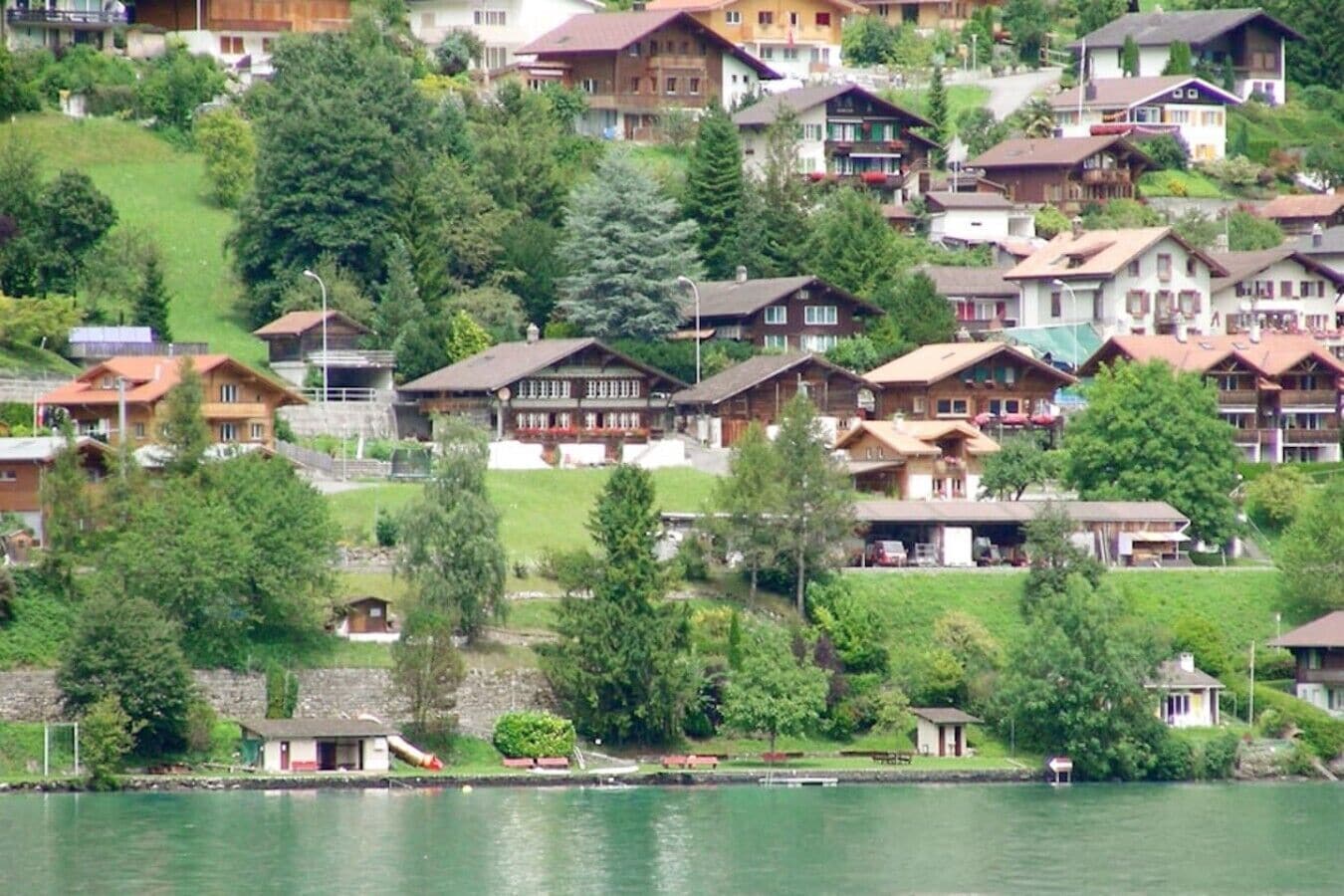Una zona residenziale sul lago con case, alcune dotate di balconi, e un piccolo molo.