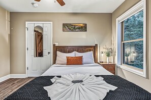 A bedroom with a bed, a door, a window, and a painting on the wall. - Hot Tub, Mtn Views & EV Charger, 1.5mi to Gatlinburg Strip (Gatlinburg)