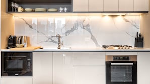 A modern kitchen with built-in appliances, a marble backsplash, and a stainless steel range hood. - Modern City Views Escape With Gym Access (Melbourne)