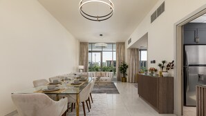 Un'area pranzo moderna con tavolo in vetro, sedie imbottite e un lampadario contemporaneo.