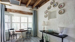 A dining area with a round table, two chairs, a black table with a white lamp, and a wall decorated with circular plates. - The Gaston Loft, Historic | Steps to Forsyth Park (Savannah)