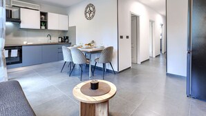 Una cucina moderna con zona pranzo, una sveglia al muro e un corridoio che conduce a una porta.