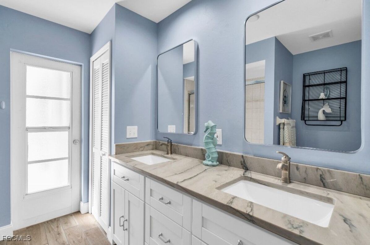 A bathroom with two sinks, a large mirror, and a white door.