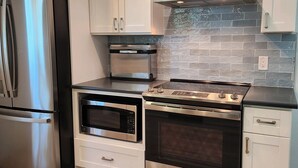 A modern kitchen with stainless steel appliances, including a refrigerator, oven, and microwave. - Cozy 2-bedroom Lakehouse in charming Avon Park (Avon Park)