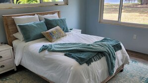 A neatly made bed with a white comforter and teal throw pillows, a matching teal throw blanket, and a patterned rug on a wooden floor. - Cozy 2-bedroom Lakehouse in charming Avon Park (Avon Park)