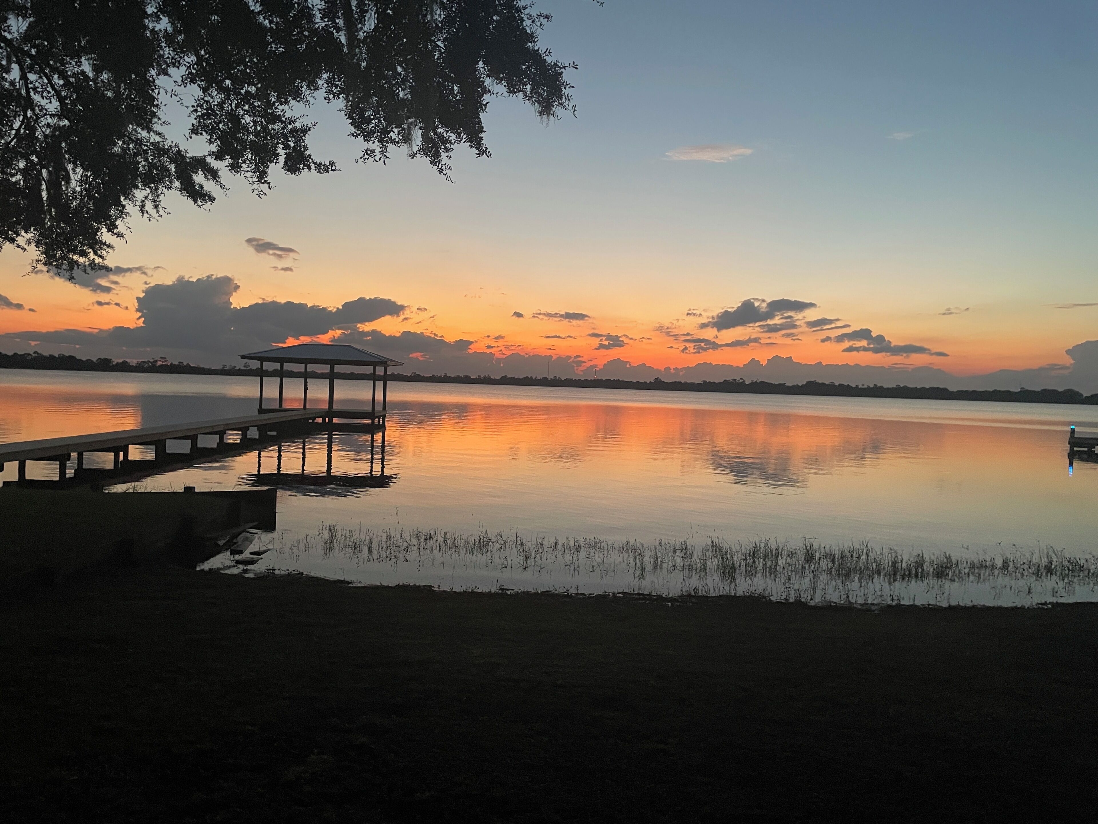 Un paysage paisible au bord d’un lac, avec une jetée en bois et un kiosque.